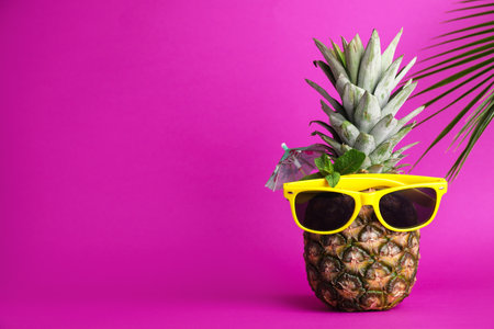 Fresh pineapple with sunglasses, umbrella and mint as summer cocktail on color background, space for textの写真素材