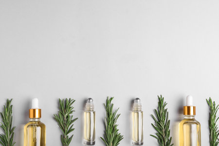 Flat lay composition with rosemary essential oil and space for text on light backgroundの写真素材