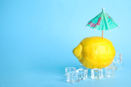 Creative composition with lemon, ice and cocktail umbrella on color background. Space for textの写真素材