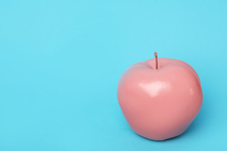Coral painted apple on light blue background. Space for textの写真素材