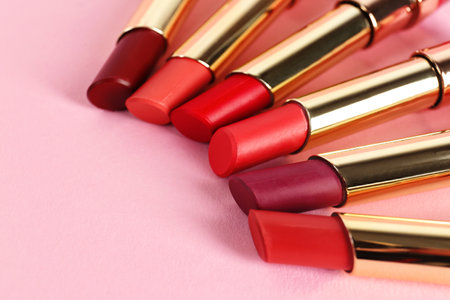 Set of bright lipsticks in gold tubes on pink background, space for textの写真素材