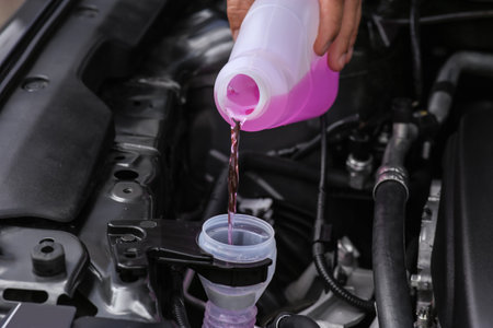 Man pouring liquid from plastic canister into car washer fluid reservoir, closeupの写真素材