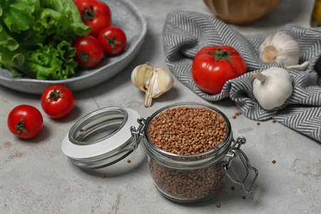 Glass jar with uncooked buckwheat on gray kitchen tableの写真素材