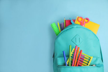 Stylish backpack with different school stationary on light blue background, top view. Space for textの写真素材