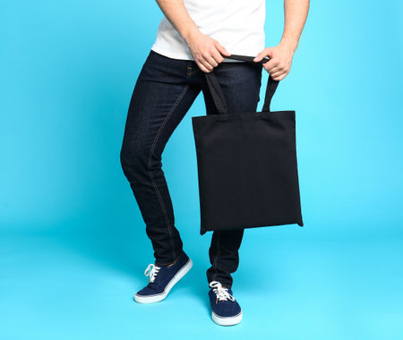 Young man with eco bag on blue background, closeupの写真素材