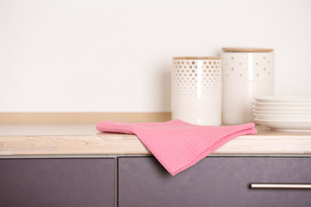Fabric pink towel on wooden table in kitchenの写真素材