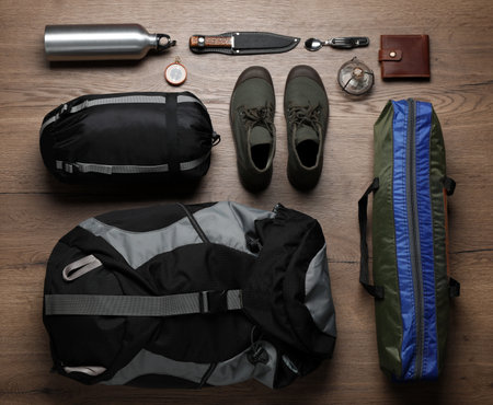 Flat lay composition with different camping equipment on wooden background