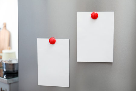 Sheets of paper and photos with magnets on refrigerator door indoors. Space for textの写真素材