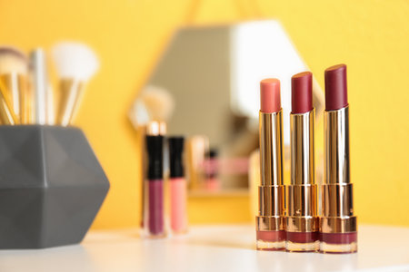 Bright lipsticks in gold tubes on dressing table, space for textの写真素材