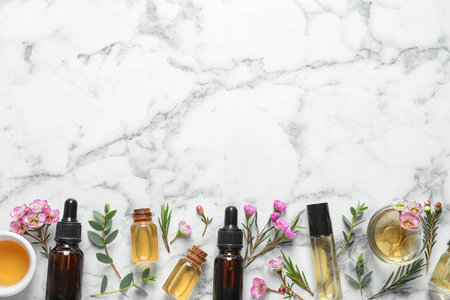 Flat lay composition with bottles of natural tea tree oil and space for text on white marble backgroundの写真素材