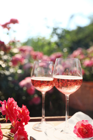 Glasses of rose wine on table in blooming gardenの写真素材