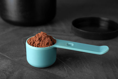 Scoop of chocolate protein powder on gray stone table
