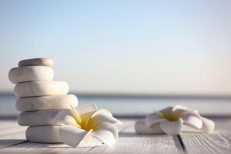 Stack of white marble stones and beautiful flower on wooden deck, space for text. Zen conceptの写真素材