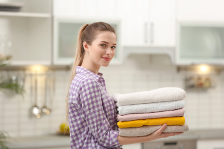 Woman holding folded clean towels in kitchen. laundry dayの写真素材