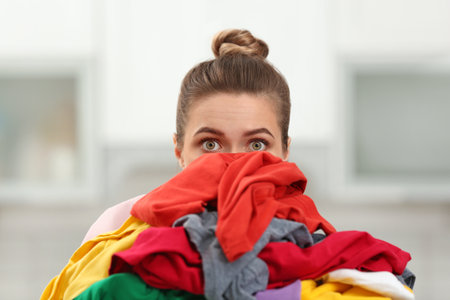 Woman holding pile of dirty laundry indoorsの写真素材