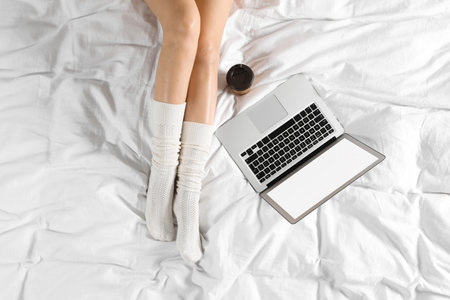 Top view of woman with laptop sitting on bed, closeup. Mockup for designの写真素材