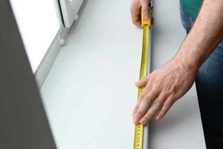 Man measuring white windowsill indoors, closeup. construction toolの写真素材