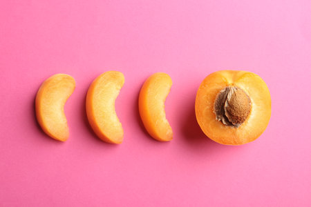 Pieces of delicious ripe sweet apricot on pink background, flat layの写真素材