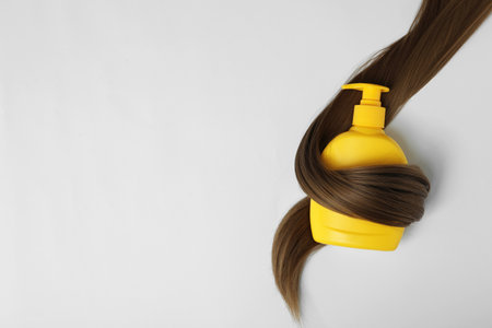 Shampoo bottle wrapped in lock of hair isolated on white, top view. natural cosmetic productsの写真素材