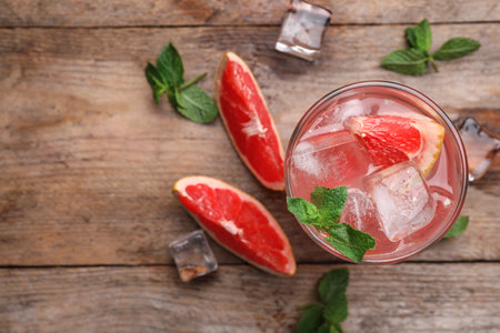 Glass of refreshing drink with grapefruit and mint on wooden table, flat lay. Space for textの写真素材