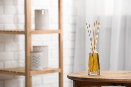 Reed air freshener on wooden table indoors, space for text