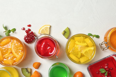 Flat lay composition with different jelly desserts on light background