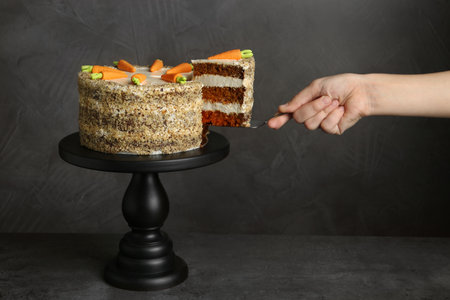 Woman taking piece of carrot cake on gray background, closeupの写真素材