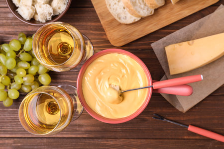 Flat lay composition with pot of cheese fondue and wine on wooden tableの写真素材