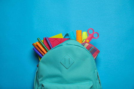 Stylish backpack with different school stationary on blue background, top viewの写真素材