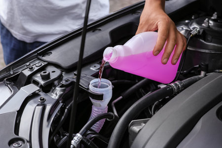 Man pouring liquid from plastic canister into car washer fluid reservoir, closeupの写真素材