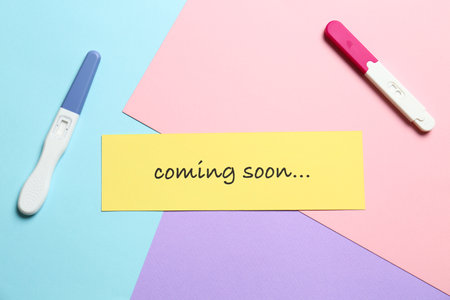 Card with words COMING SOON and pregnancy tests on color background, flat layの写真素材
