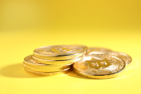 Shiny bitcoins on yellow background. digital currencyの写真素材