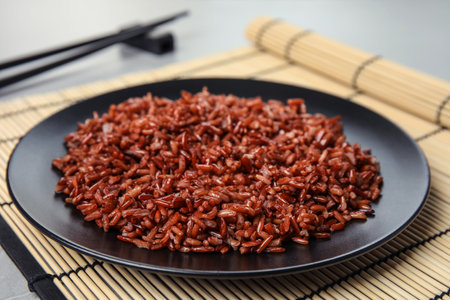 Plate with delicious cooked brown rice on tableの写真素材