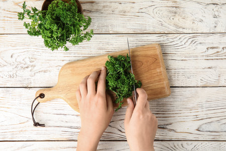 Woman cutting fresh green parsley at white wooden table, top viewの写真素材
