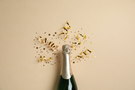 Bottle of champagne with gold glitter and confetti on beige background, flat lay. Hilarious celebrationの写真素材