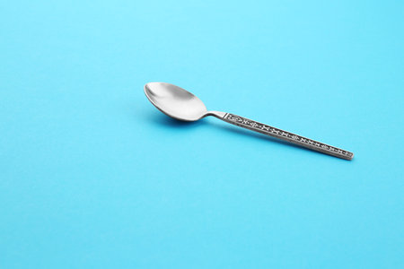 Clean empty vintage tea spoon on blue background, space for textの写真素材