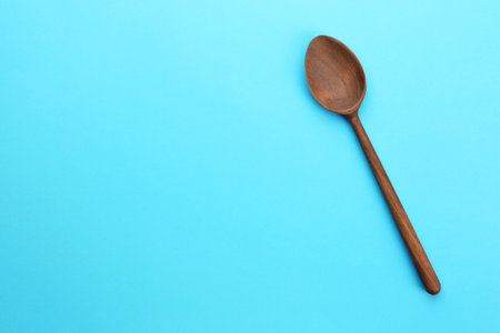 Clean empty wooden spoon on blue background, top view. Space for textの写真素材