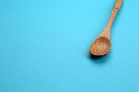 Clean empty wooden spoon on blue background, space for textの写真素材