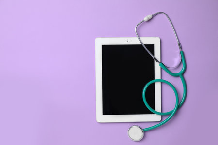 Tablet and stethoscope on lilac background, top view with space for text. Gynecology careの写真素材