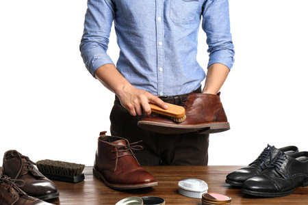 Man cleaning leather shoe at wooden table against white background, closeupの写真素材
