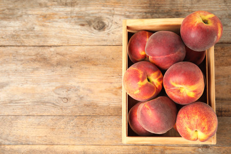 Crate with tasty peaches on wooden table, top view. Space for textの写真素材