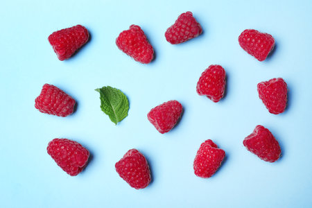 Flat lay composition with delicious ripe raspberries on blue backgroundの写真素材