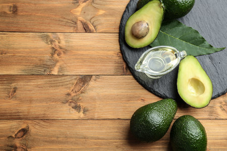 Composition with natural oil and avocados on wooden background, flat lay. Space for textの写真素材