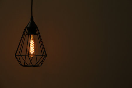 Hanging lamp bulb in chandelier against dark background, space for textの写真素材