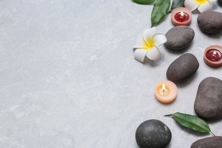 Composition with spa stones and lit candles on gray marble background, space for textの写真素材