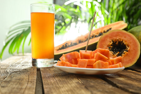 Fresh papayas and juice on wooden table against blurred backgroundの写真素材