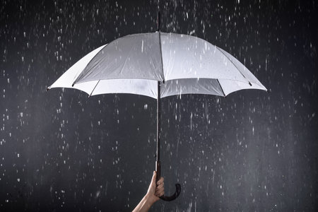 Woman holding white umbrella under rain on dark background, closeupの写真素材