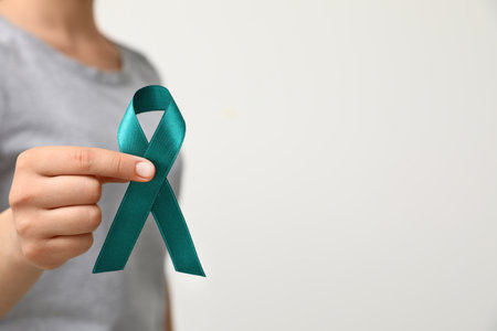 Woman holding teal awareness ribbon against light background, closeupの写真素材
