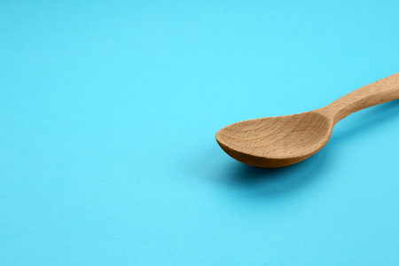 Clean empty wooden spoon on blue background, space for textの写真素材