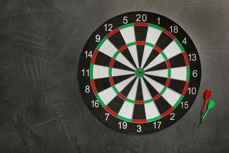 Dart board with color arrows on gray stone background, top view. Space for textの写真素材